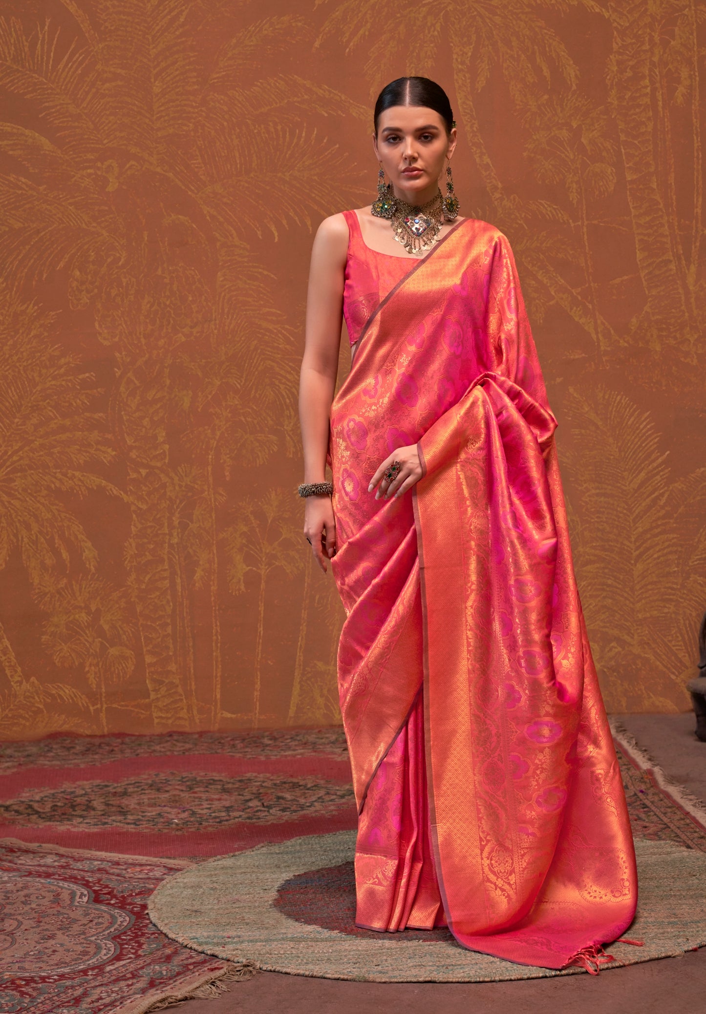 A woman modeling a peach-colored saree with a floral design, showcasing the fabric's texture and color.