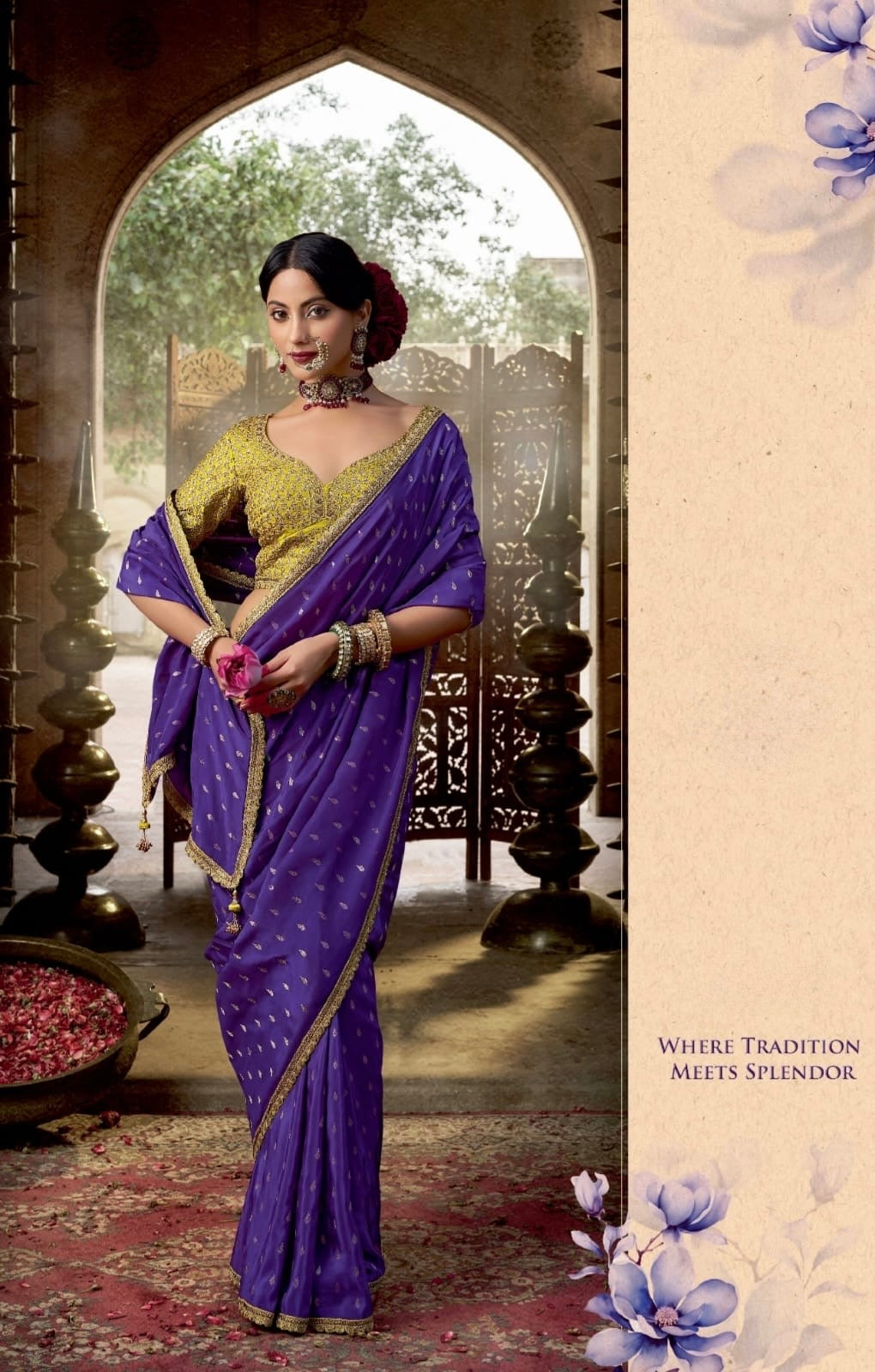 Woman in a purple saree with gold border standing in an archway.