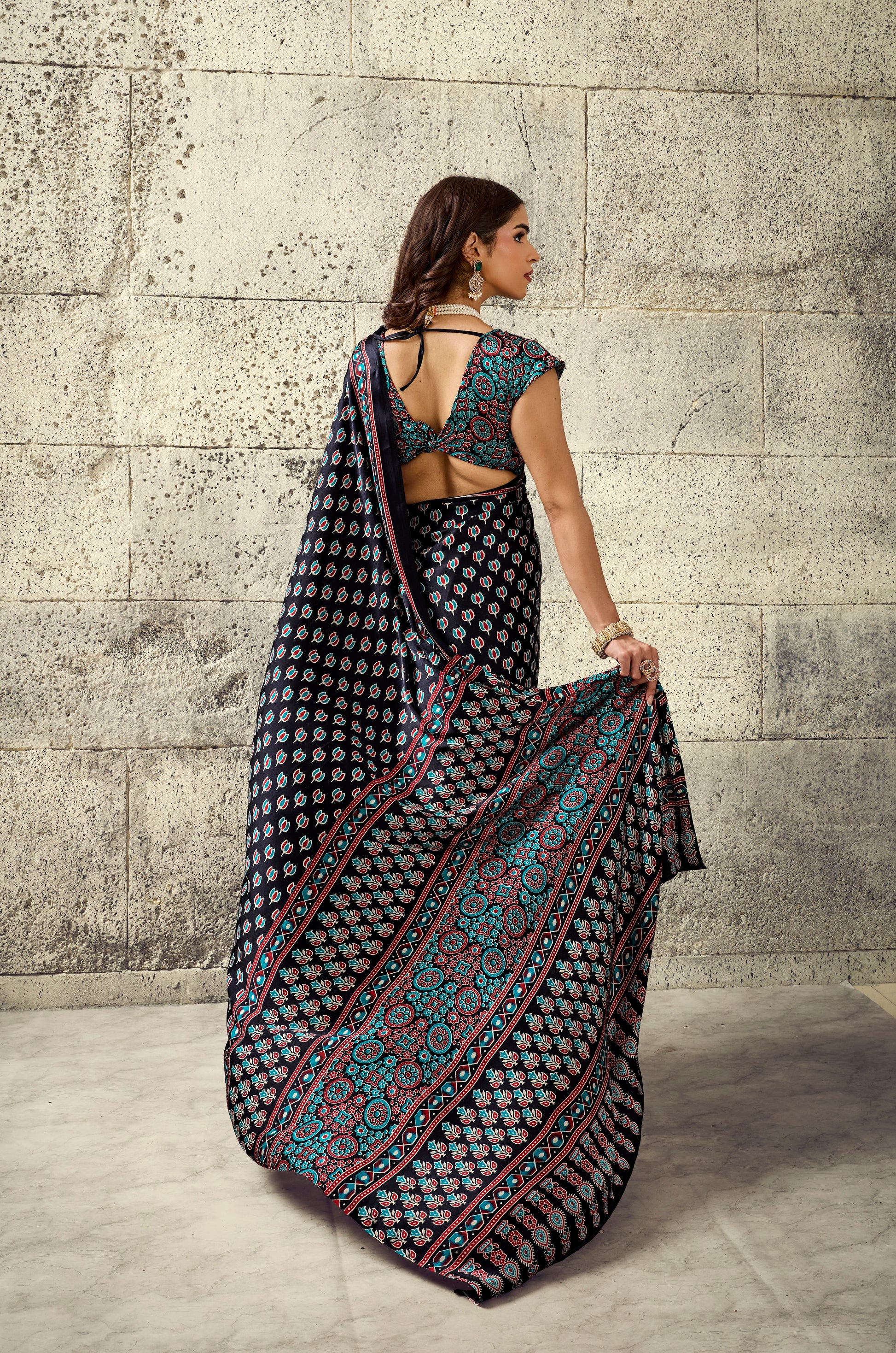 Dark printed saree draped back view, sleeveless blouse with turquoise trim and tie