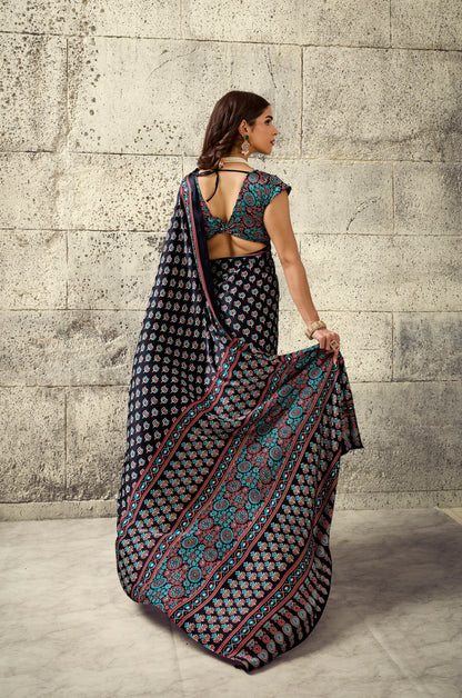 Dark printed saree draped back view, sleeveless blouse with turquoise trim and tie