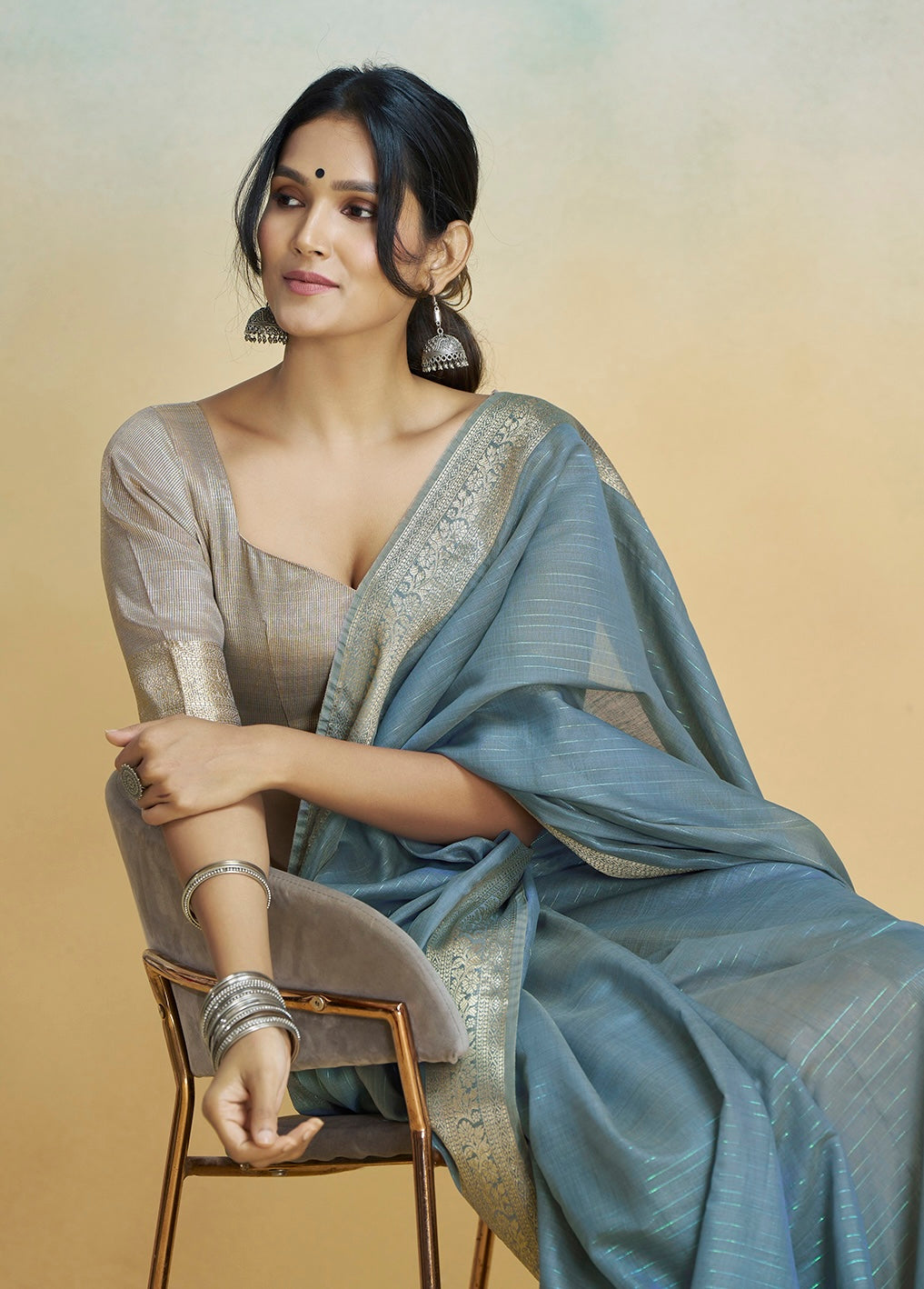 Slate grey ready-to-wear saree with gold-toned border and draped pallu, paired with blouse