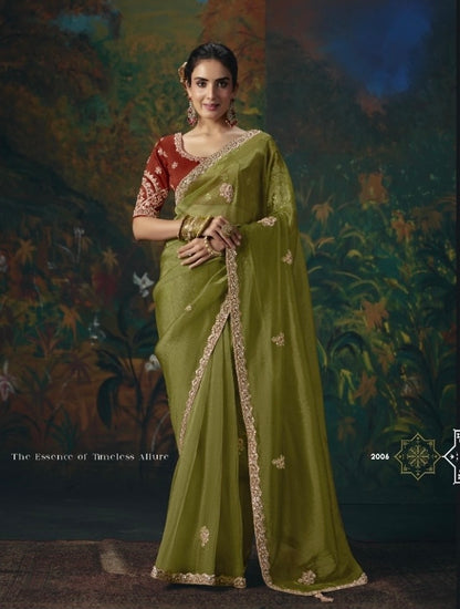Olive green tissue silk saree with gold floral accents and ornate border, worn with a red blouse