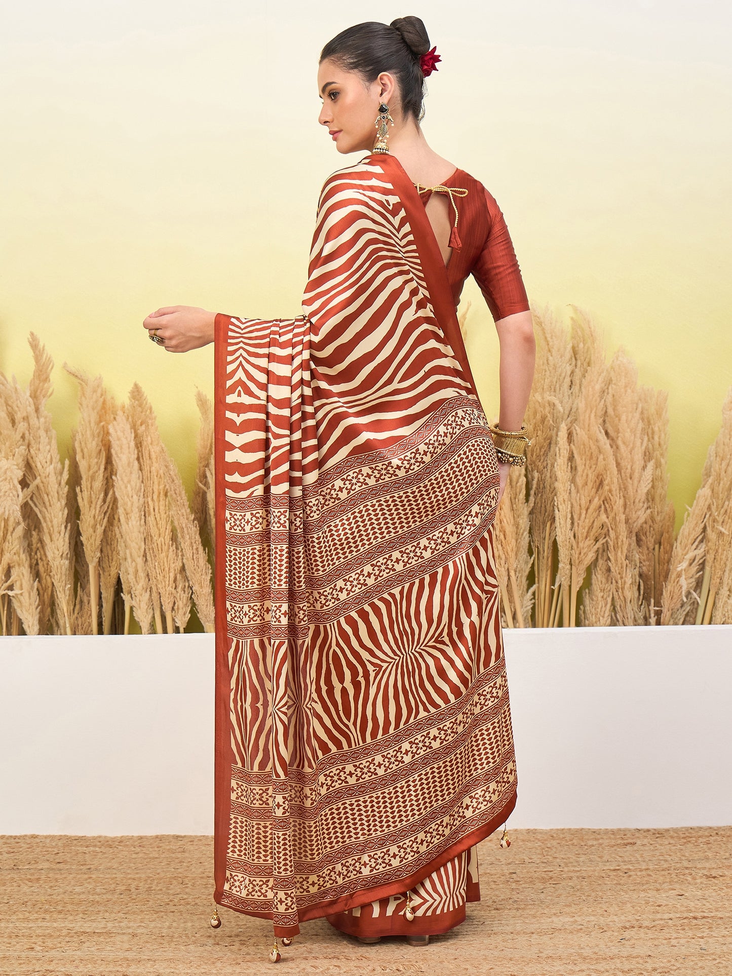 Rust-orange and cream zebra-striped saree with gold border and pleated drape