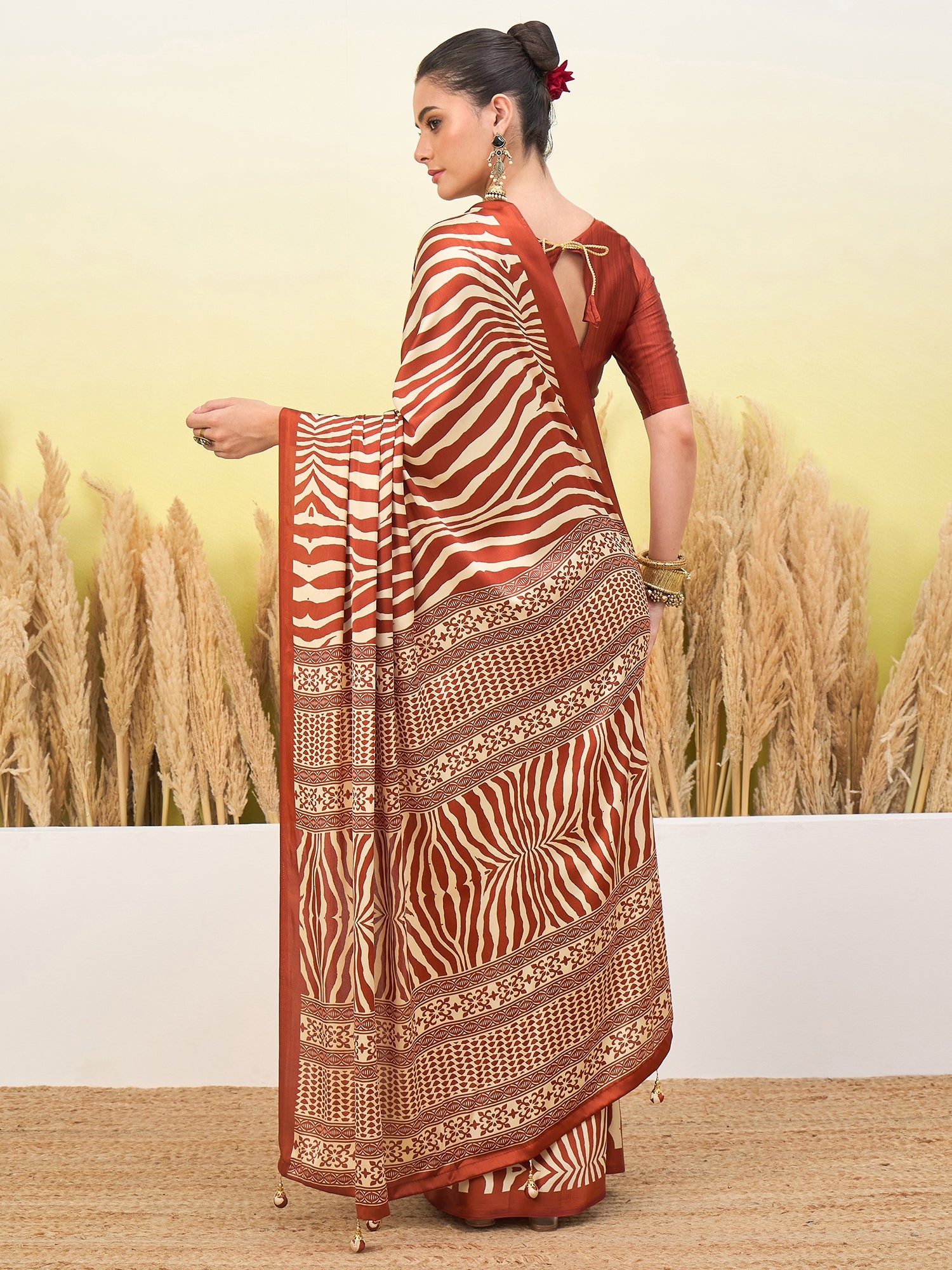 Rust-orange and cream zebra-striped saree with gold border and pleated drape