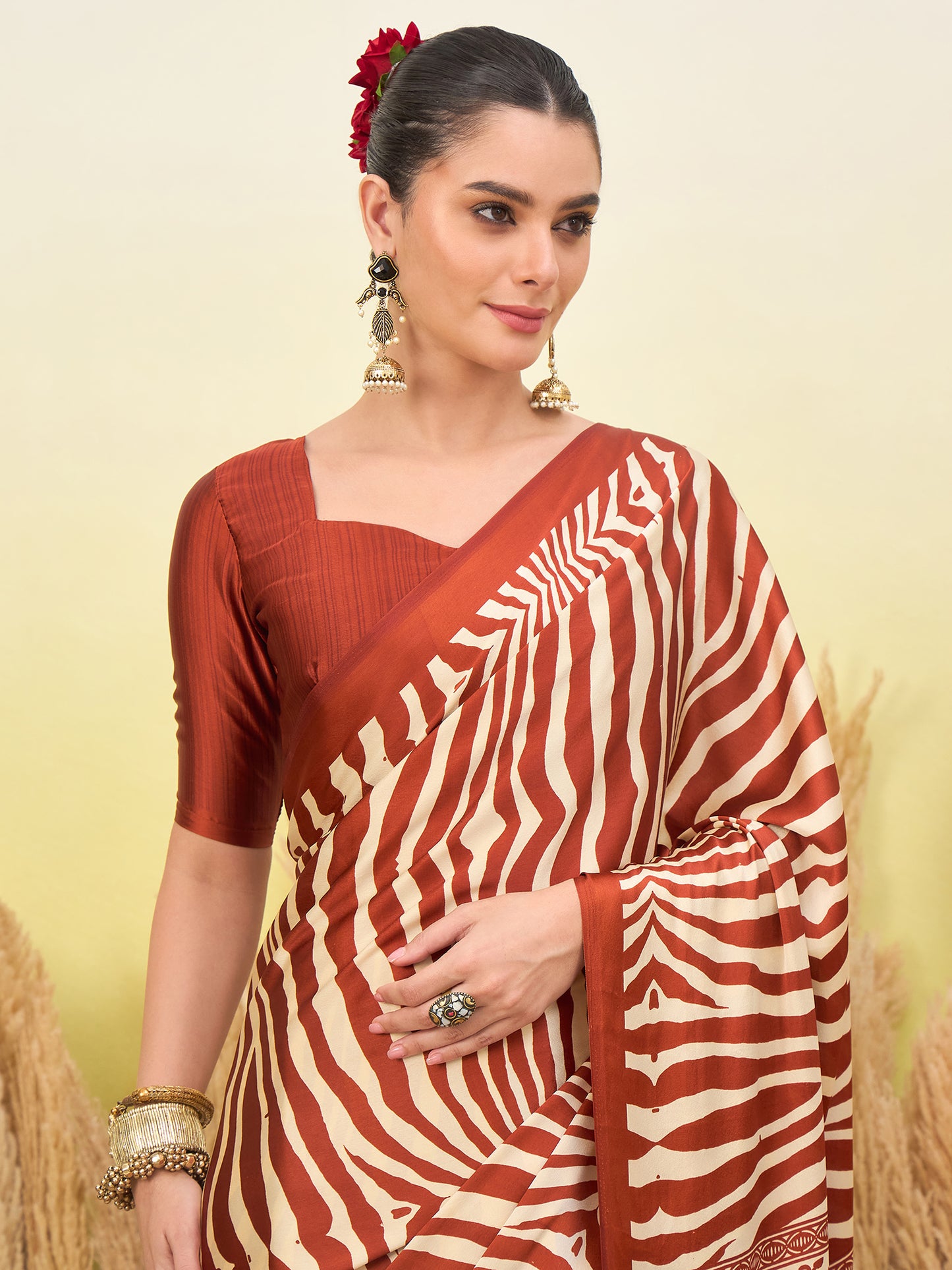 Rust-orange zebra-striped saree with draped pallu and gold border, close-up