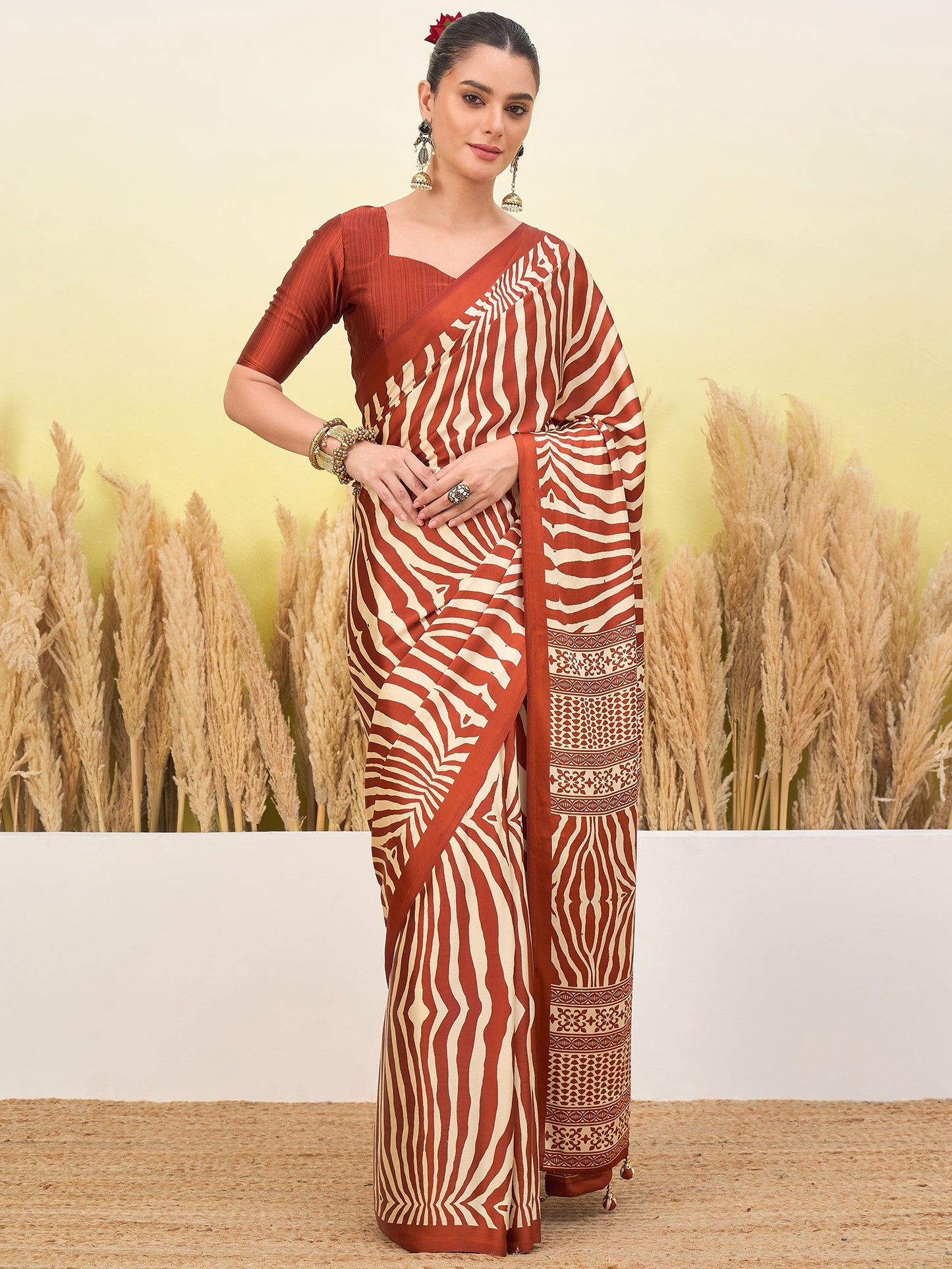 Rust-orange zebra-striped saree with gold border and short-sleeve blouse, standing