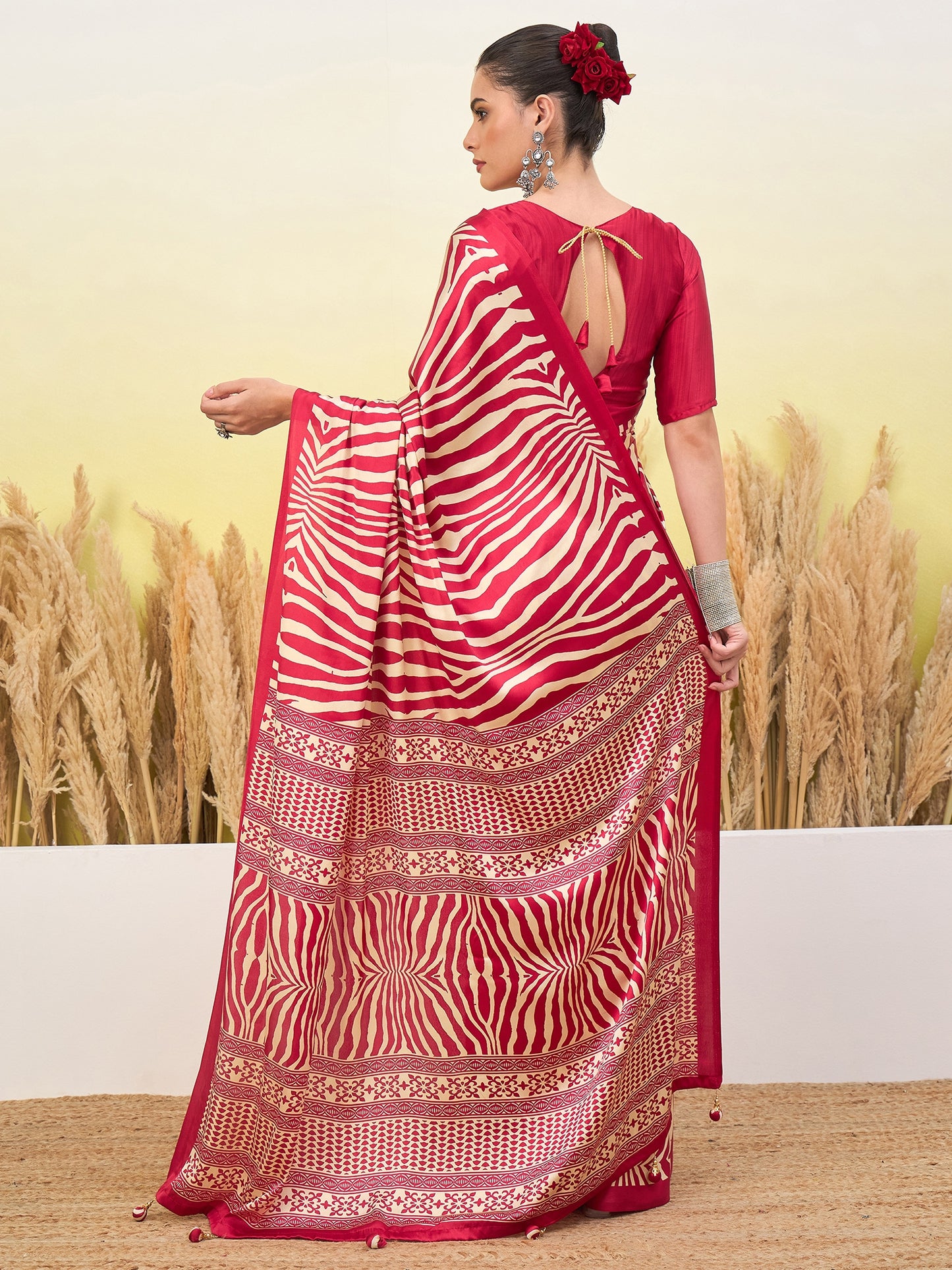 Red sari draped over shoulder with white zigzag stripes and gold hem, open-back blouse