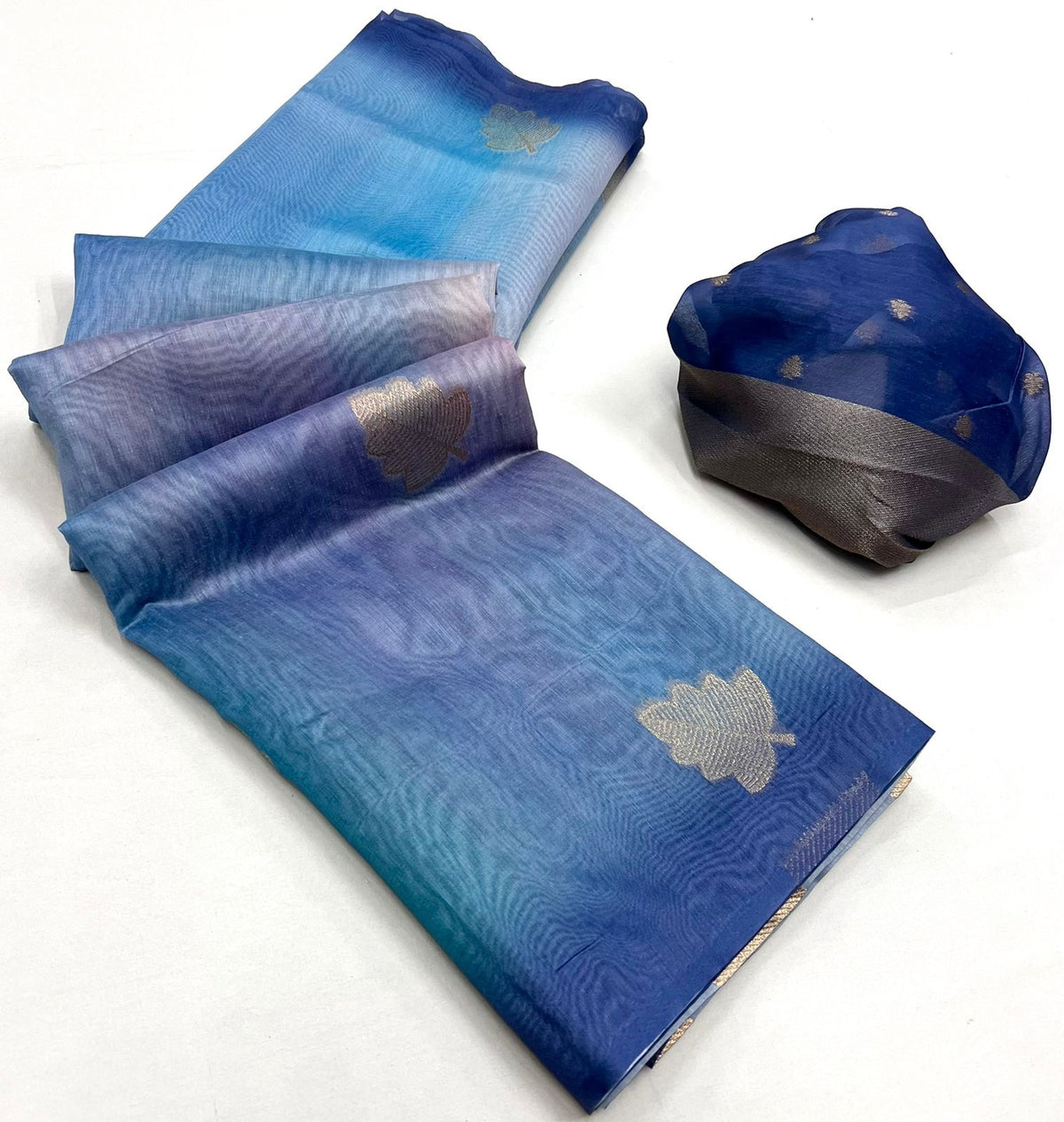 Slate blue printed linen saree with gold leaf motifs, folded with blouse piece