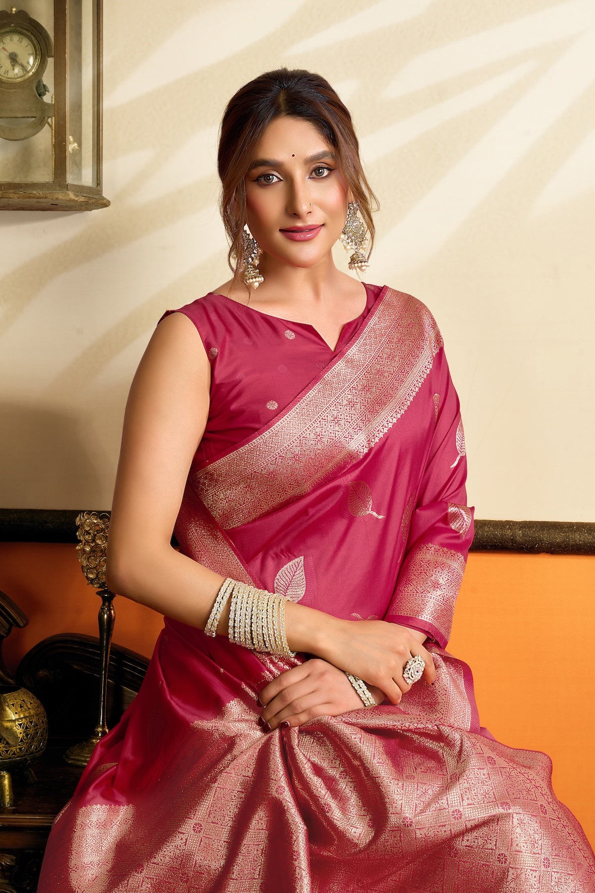Pink silk saree with gold border and leaf motifs, one-shoulder drape, elegant close-up