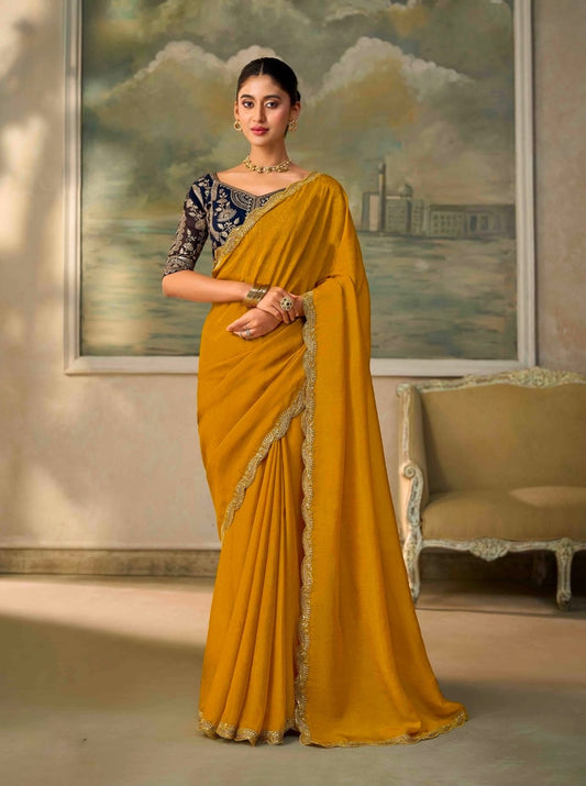 Mustard cocktail saree with dark blouse and metallic border, draped with pleats