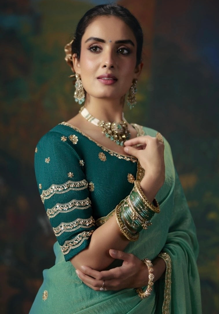 Sea green silk saree drape and dark teal blouse with gold embroidered sleeve bands