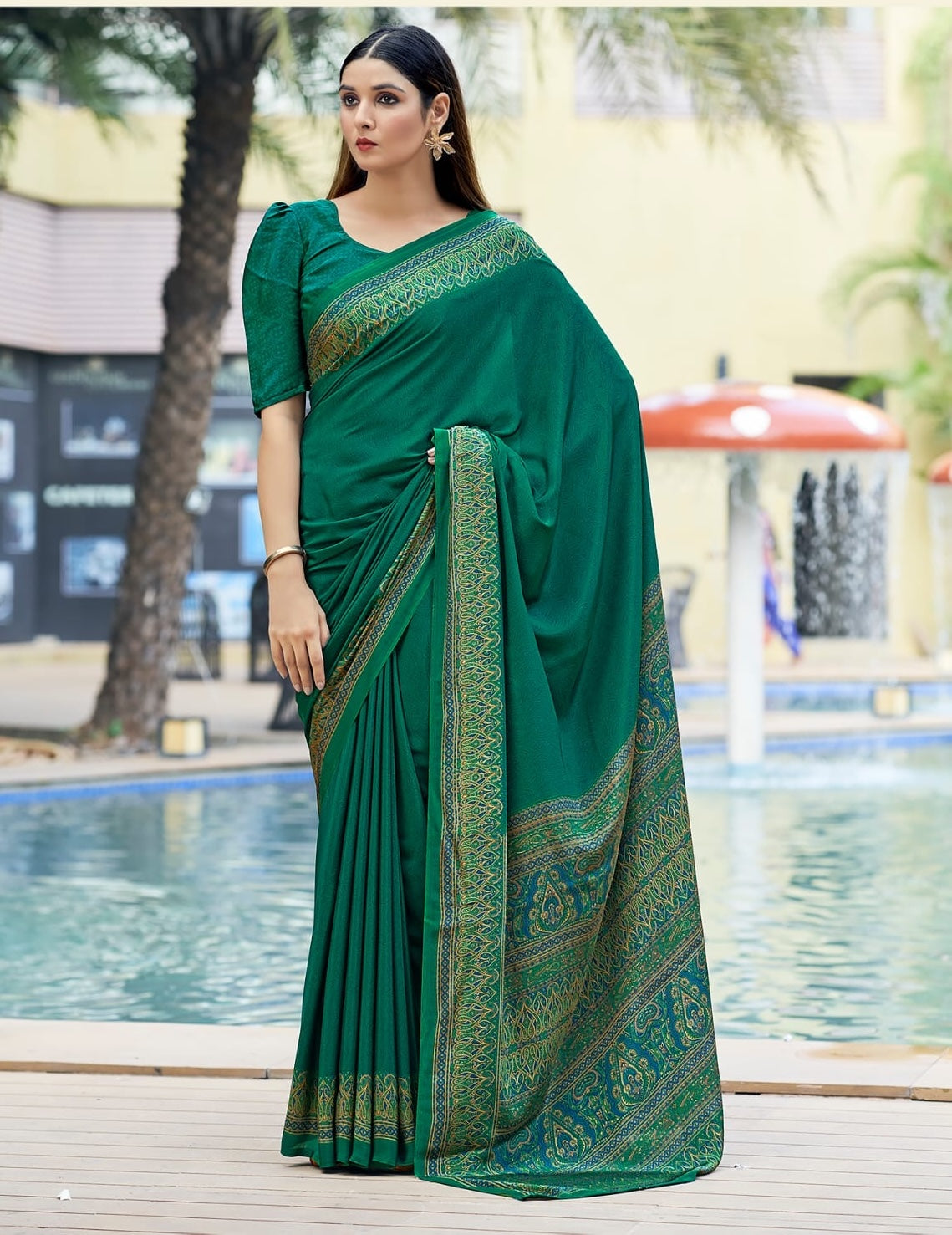 Bottle green crepe silk saree with gold-toned patterned border and short-sleeve blouse