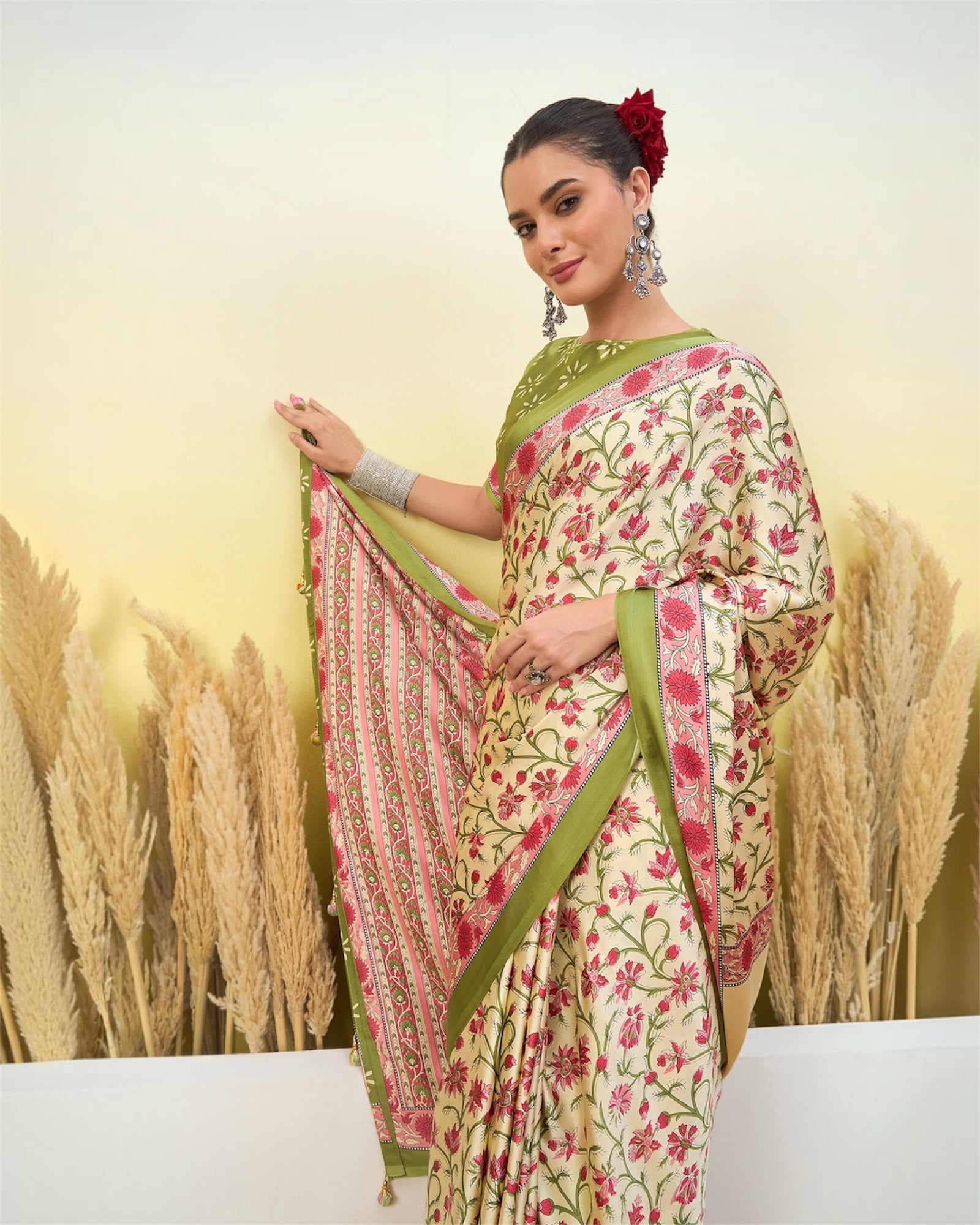 Ivory crepe silk saree with green border and red floral print, side drape view.