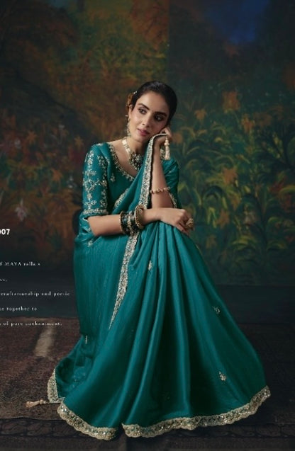 Turquoise ready-to-wear saree draped to show its pleats, gold border, and embroidered blouse