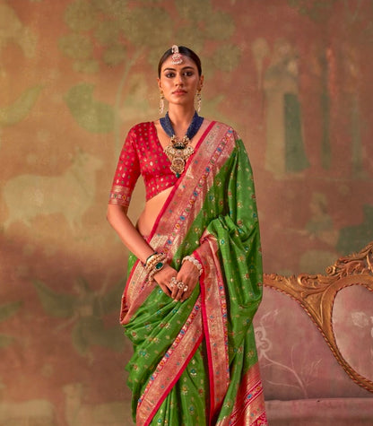 Leaf green patola silk saree with red border and floral motifs, draped over blouse