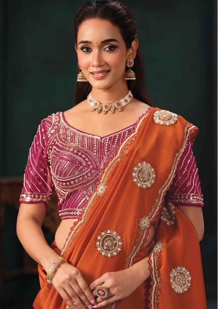 Orange saree draped over a magenta embroidered blouse, showing jeweled motifs and border