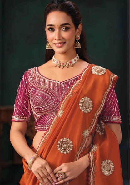 Orange saree draped over a magenta embroidered blouse, showing jeweled motifs and border