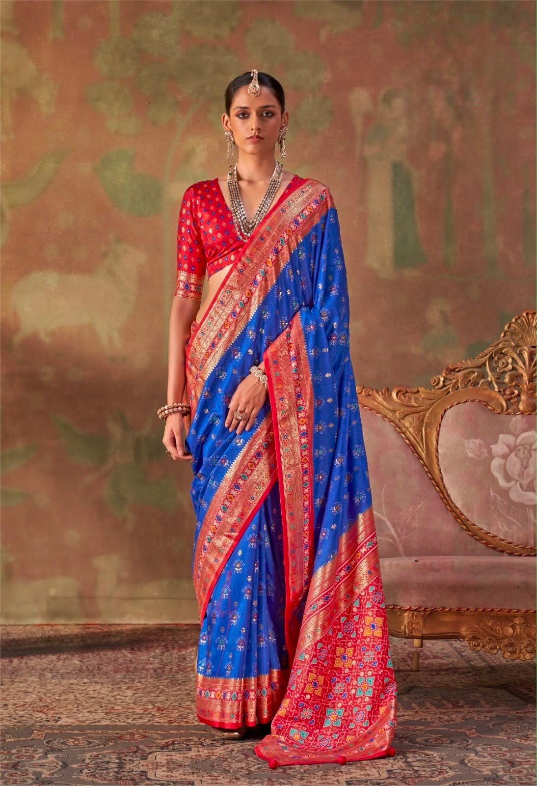 Royal blue silk saree with red and gold border, draped pallu and short-sleeve blouse