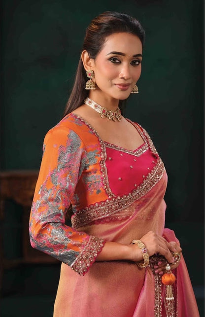 Peach-pink saree with embellished border and bright pink blouse with patterned orange sleeves.